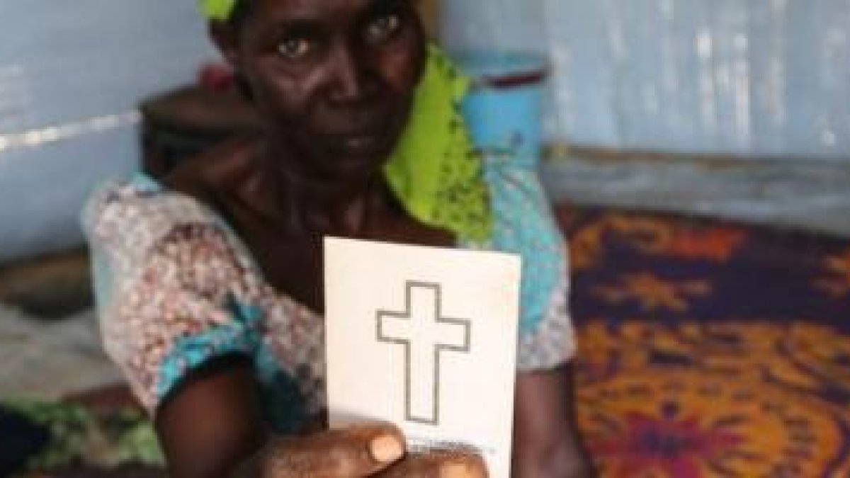 Godiya Ousman con su tarjeta-cartilla de bautismo - ha huido de Nigeria para salvar su vida y mantener su fe