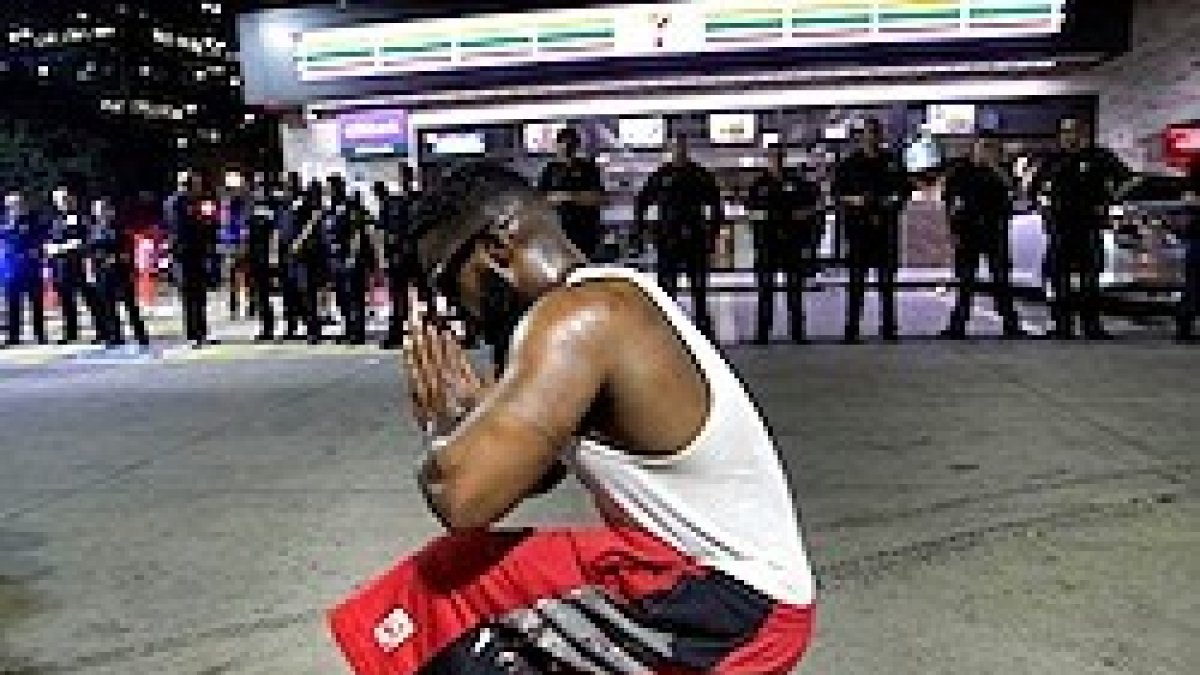 Una persona en oración cerca de lugar donde se produjo el tiroteo.