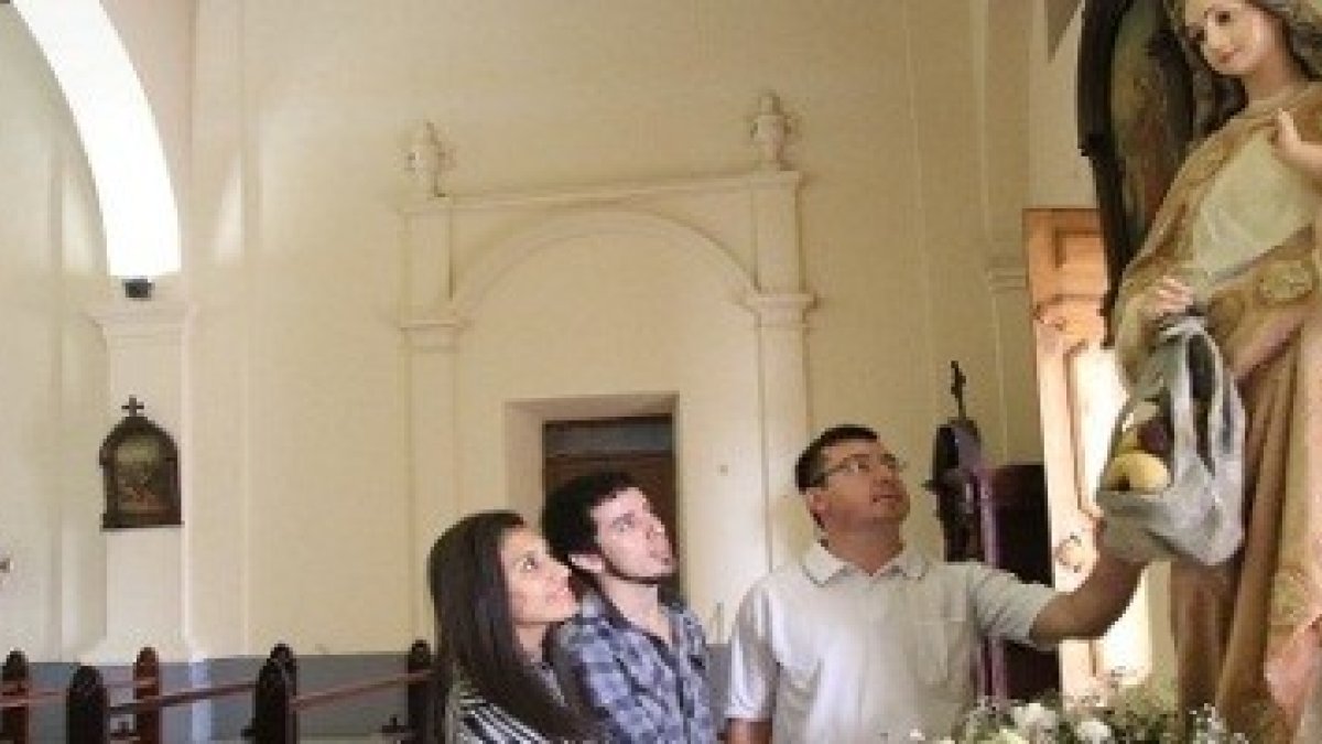 La imagen representa a la Virgen cargada con comida en la bolsa y al niño en el otro brazo.