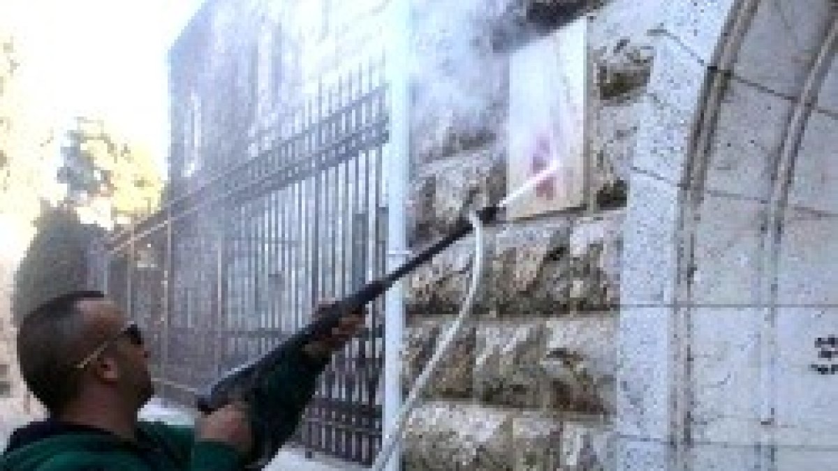Limpiando las pintadas anticristianas en la entrada de la Basílica de la Dormición de la Virgen en Jerusalén