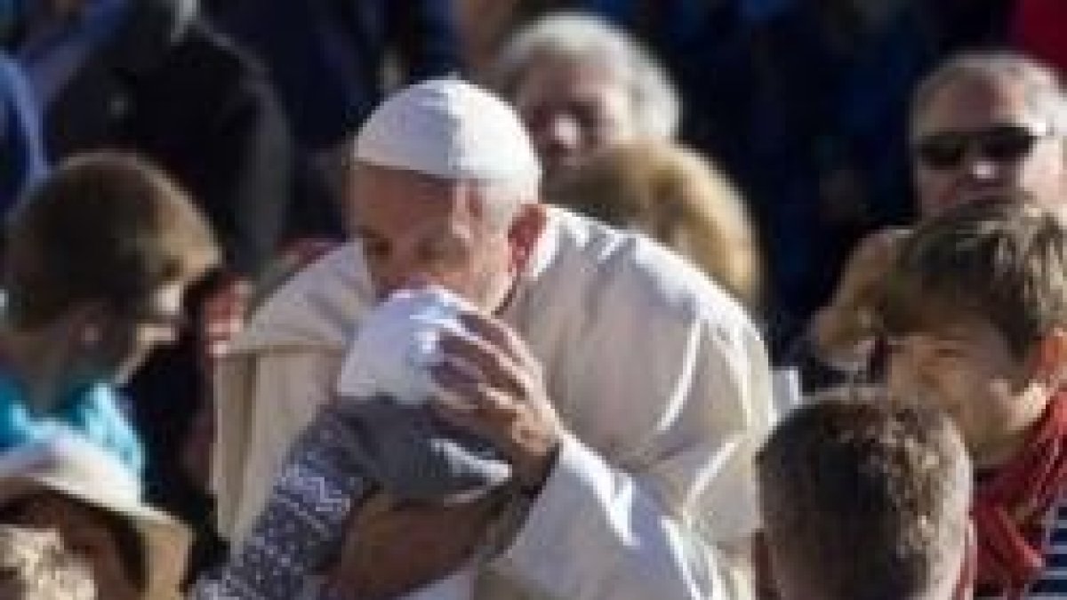 Francisco besa un bebé mientras saluda peregrinos en la audiencia de los miércoles