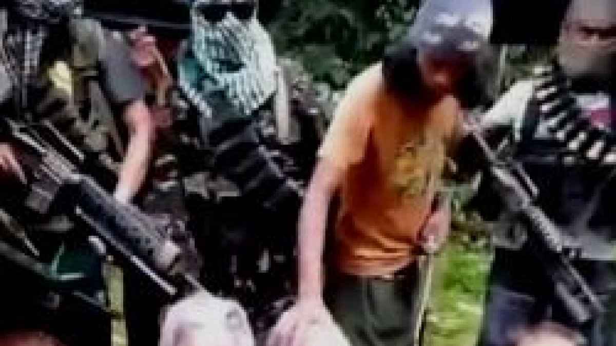 Escena de vídeo de los secuestradores en la que apoyan la mano sobre John Ridsdel, que ahora han decapitado