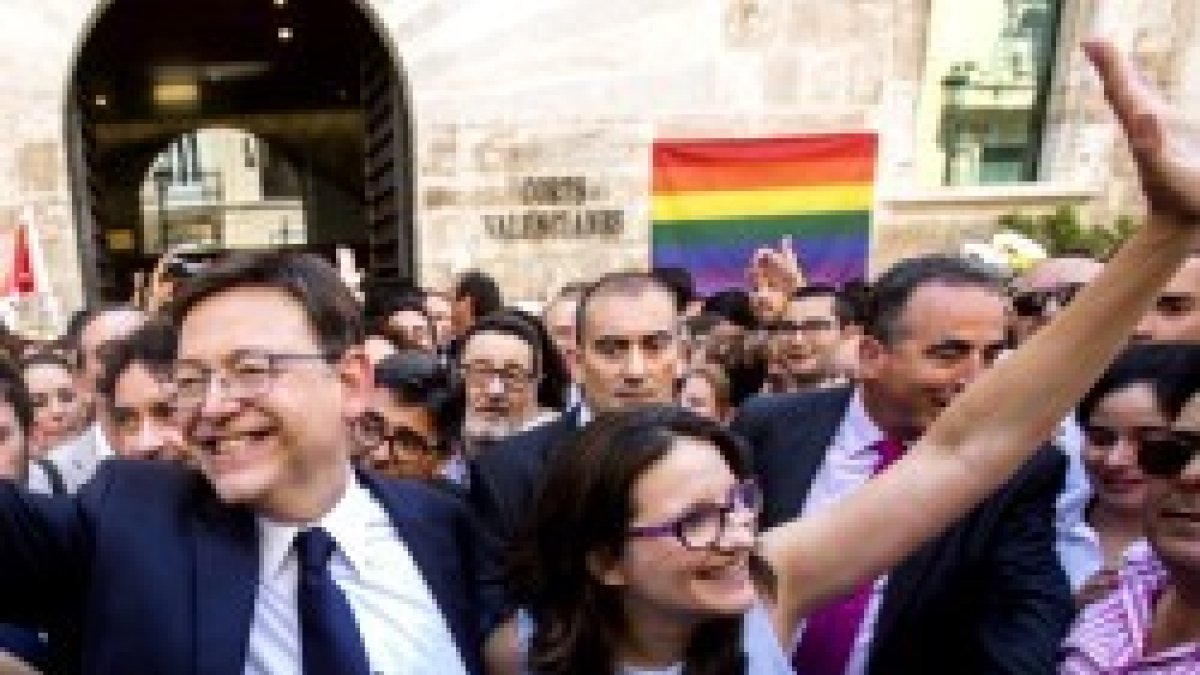 Ximo Puig, socialista, y Monica Oltra, de Compromís, con la bandera del lobby al que sirven