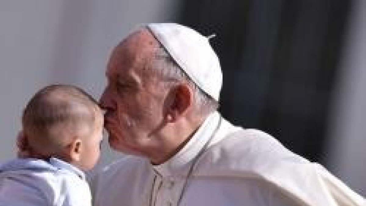 El Papa Francisco besa un bebé que le presentan en la audiencia del miércoles