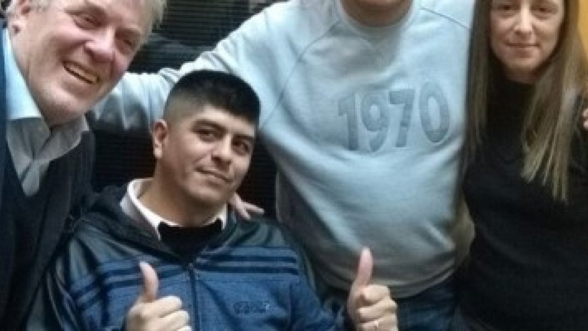 Maximilano hace un gesto de optimismo, acompañado de amigos y parientes que le apoyan