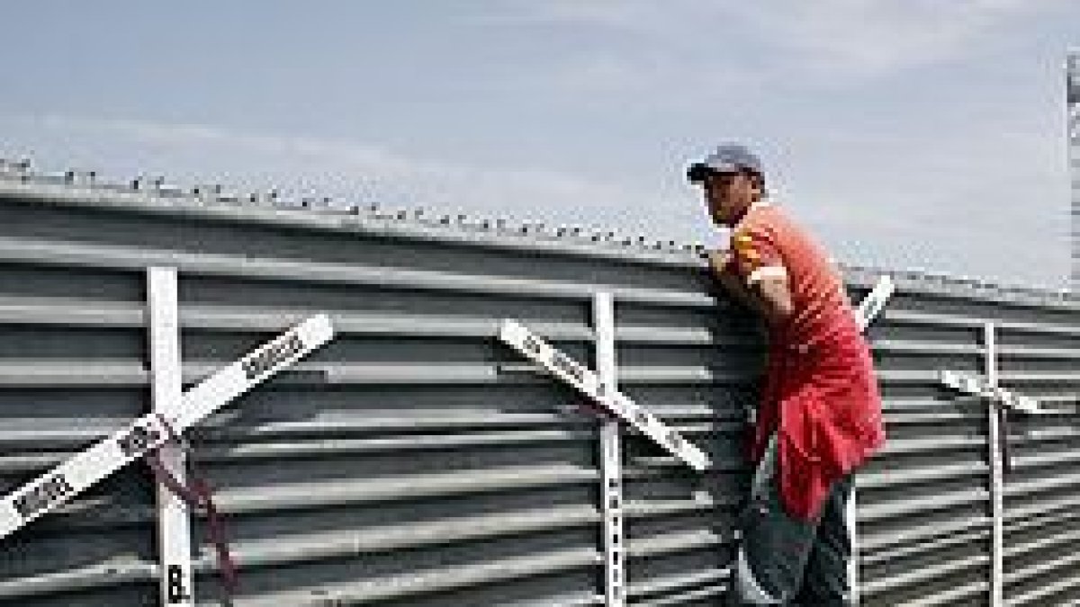 Un hombre se asoma a la frontera entre San Diego y Tijuana, entre México y EEUU