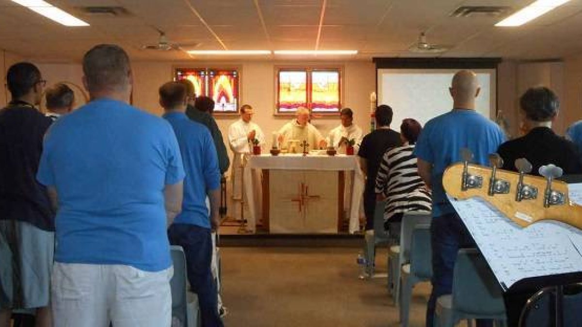 El arzobispo Miller de Vancouver celebrando misa en la cárcel en presencia de los reclusos