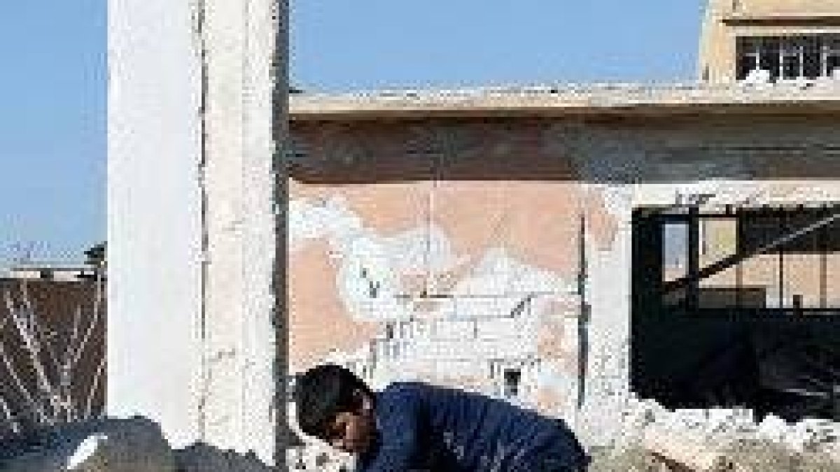 Un niño sirio hurga entre los escombros de los bombardeos