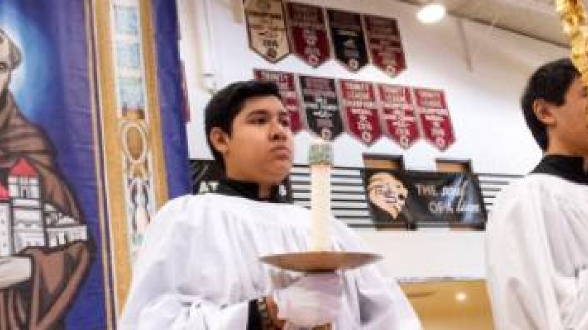 Monaguillos y estudiantes hispanos en una escuela católica de California, en una celebración con un tapiz del santo fundador español