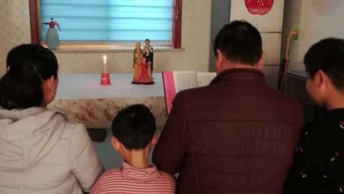 Una familia católica guarda el domingo rezando en casa con la Biblia, velas y una imagen sagrada... no se puede ir a las iglesias