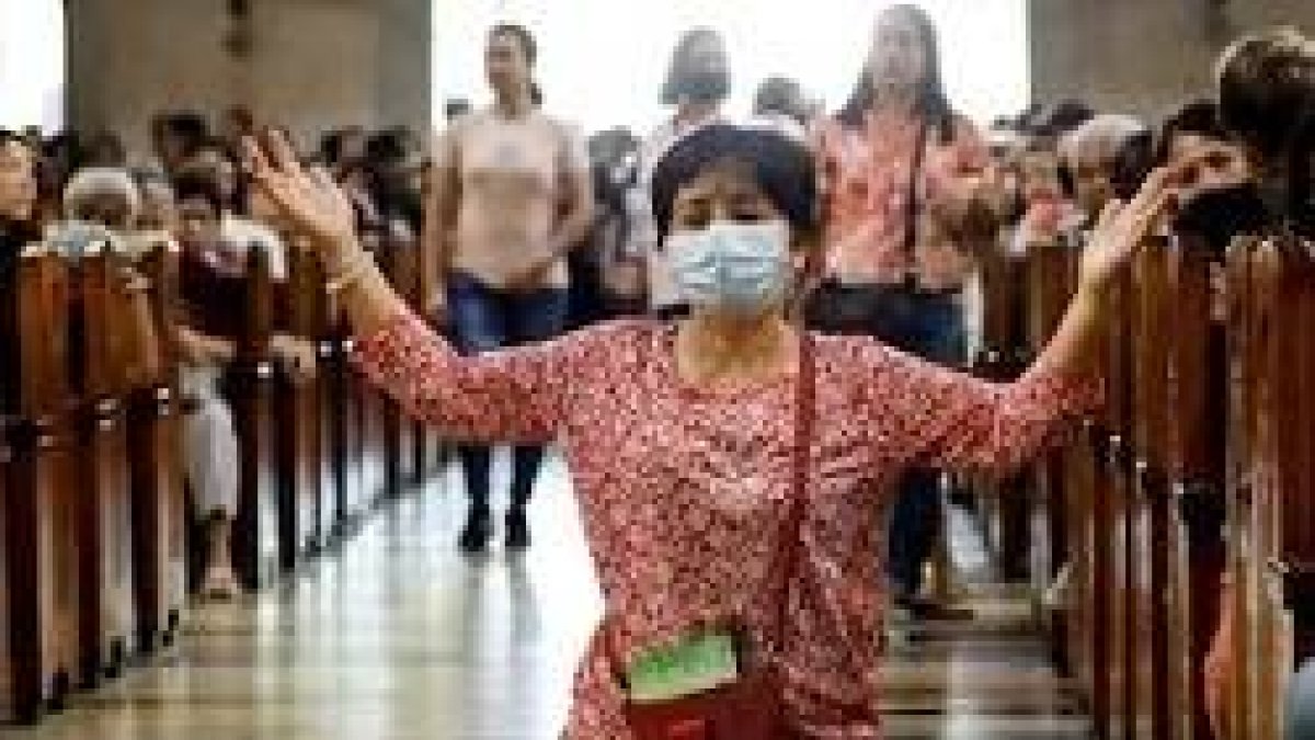 Una mujer reza en una iglesia de Asia... pero en varios países ya no es posible hacerlo en misa... Singapur e Italia, por ejemplo, y ahora Malasia