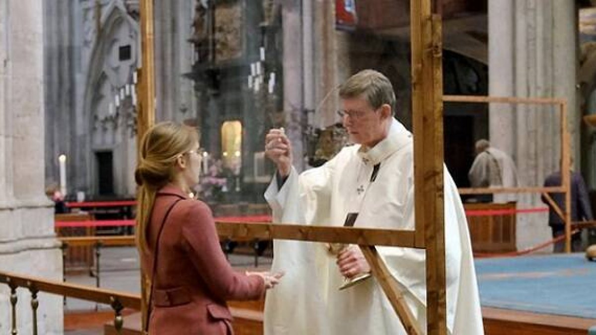 El cardenal Woelki y otros ministros de la comunión reparten la comunión tras unas mamparas de metacrilato