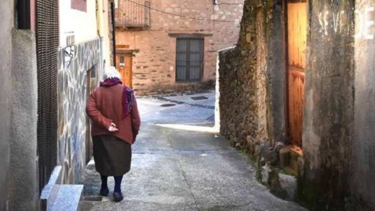 Una anciana pasea por un pequeño pueblo de España