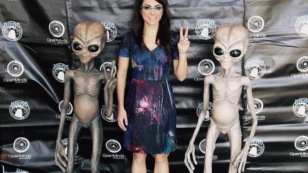 Una visitante del International Ufo Congress -que se celebra desde 1991- se fotografía con dos muñecos