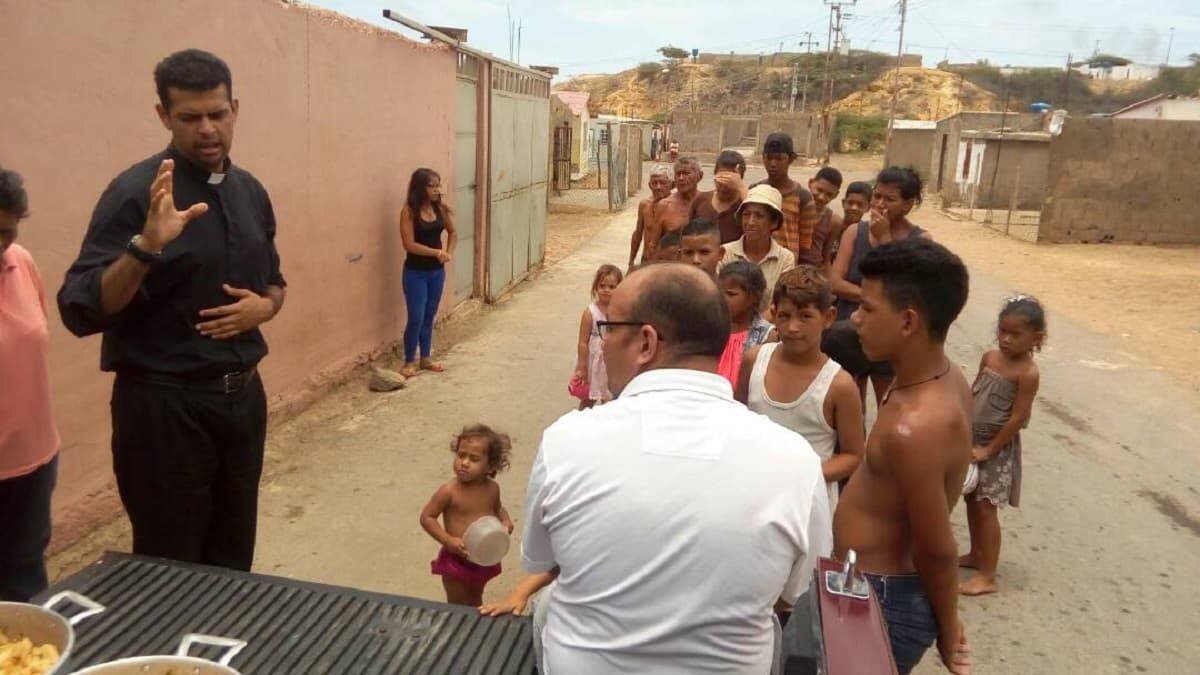 El padre Robinson, en la imagen bendiciendo una comida para las personas pobres que hacen cola