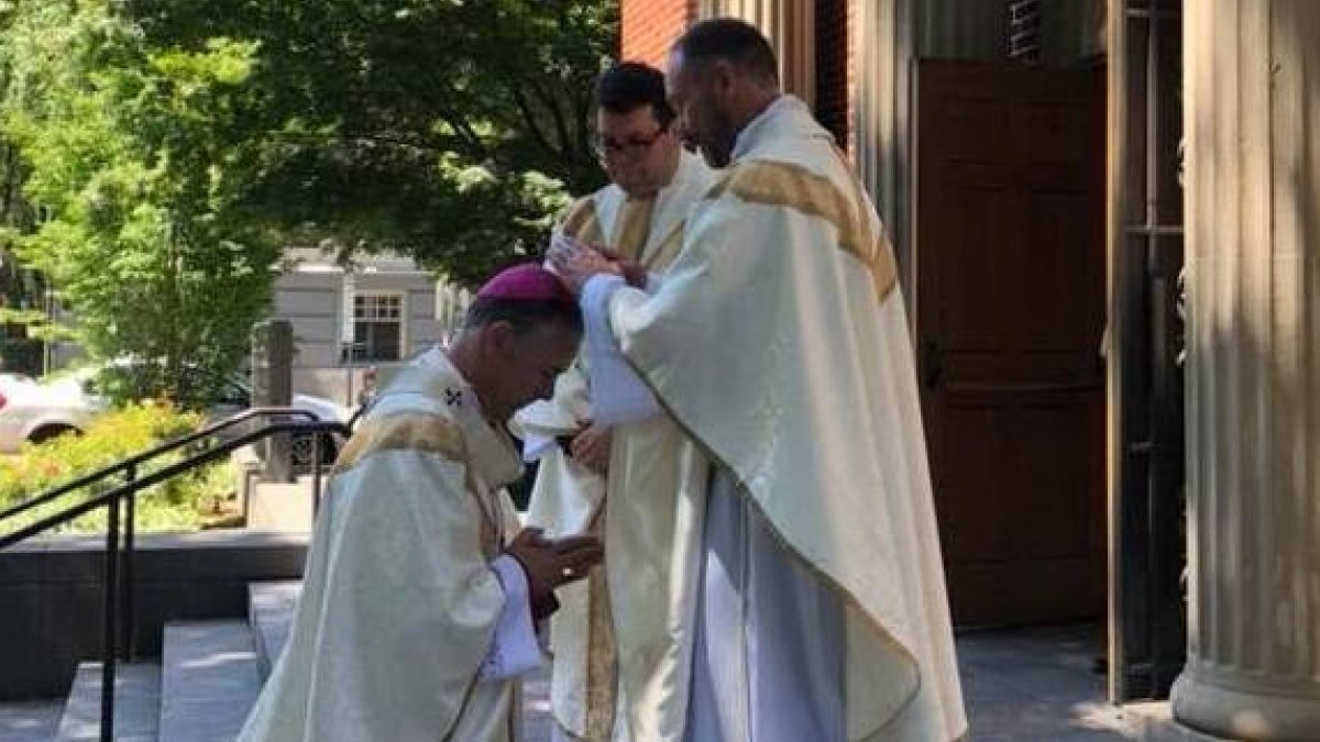 Brent Crowe bendice al arzobispo Sample en 2018, tras ser ordenado sacerdote