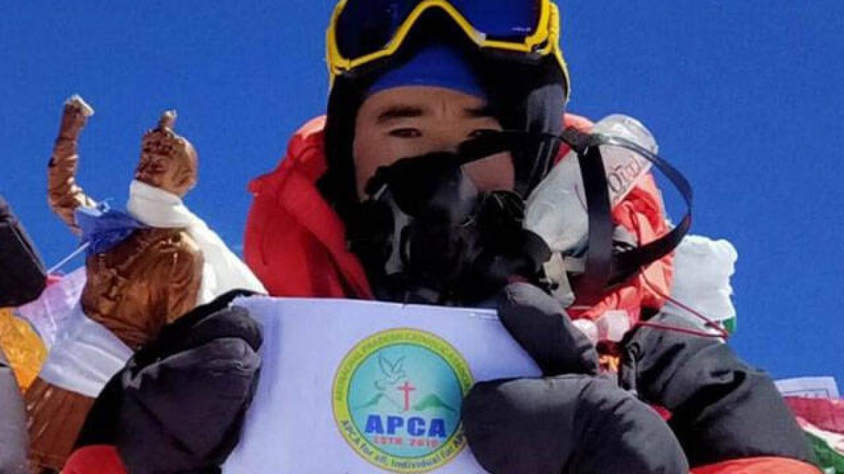 Abraham Tagit Sorang mostrando la bandera de la Asociación Católica de Arunachal Pradesh
