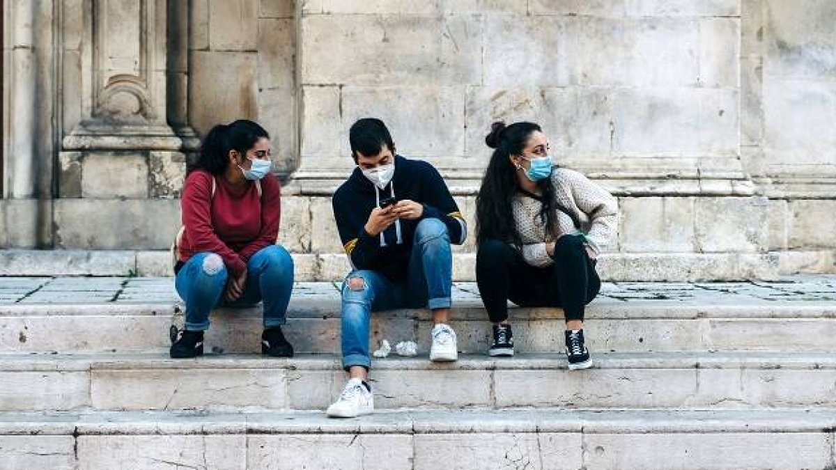 Jóvenes miran el móvil en la escalera de una iglesia antigua - Foto de Gabriella Clare Marino en Unsplash