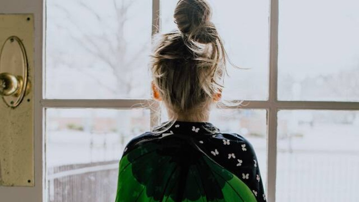 Una niña mira por el cristal de la puerta... quizá teme la guerra, o espera que vuelva alguien... foto de Kelly Sikkema en Unsplash