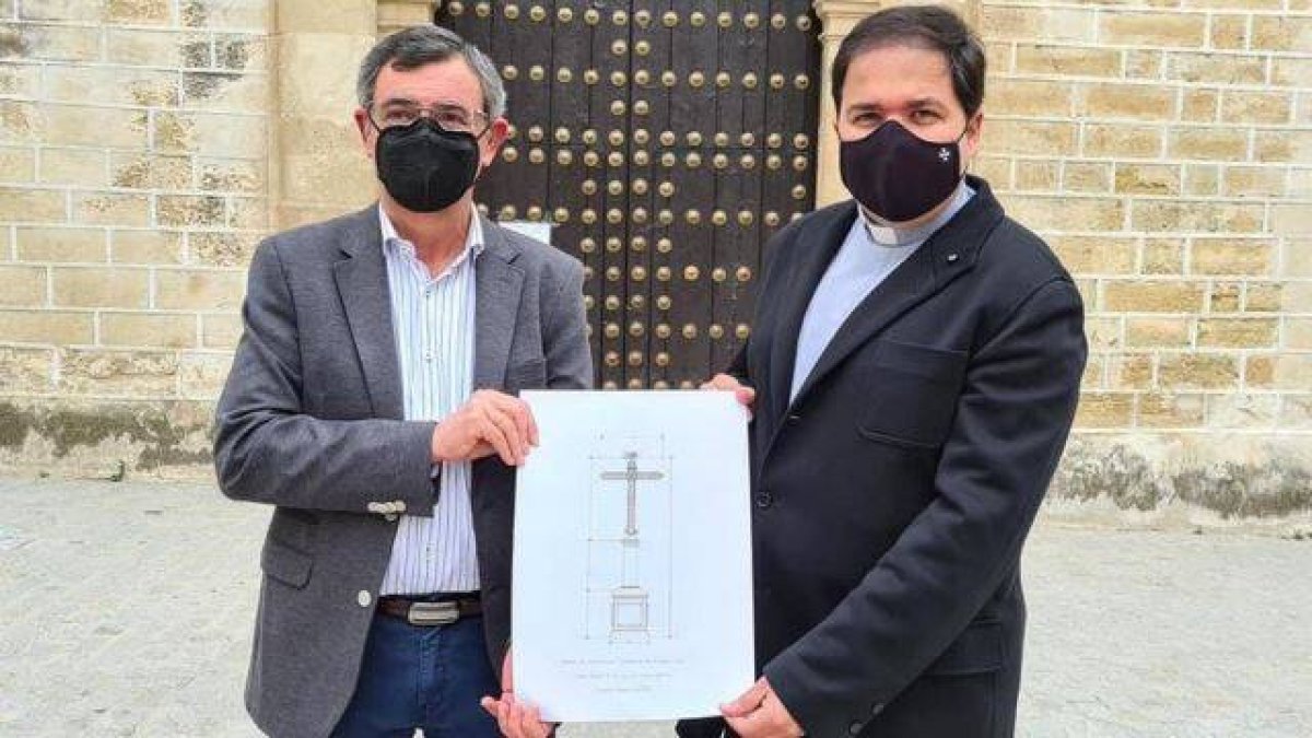 El presidente de la Agrupación de Cofradías, José Cabezas, y el párroco de Aguilar, Pablo Lora sostienen el boceto de la nueva cruz.