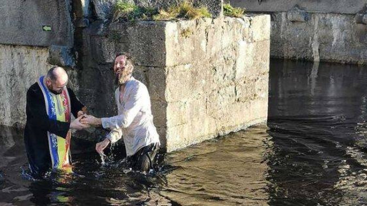 Un sacerdote ortodoxo rumano bautiza en un río irlandés al escrito inglés Paul Kingsnorth en 2021