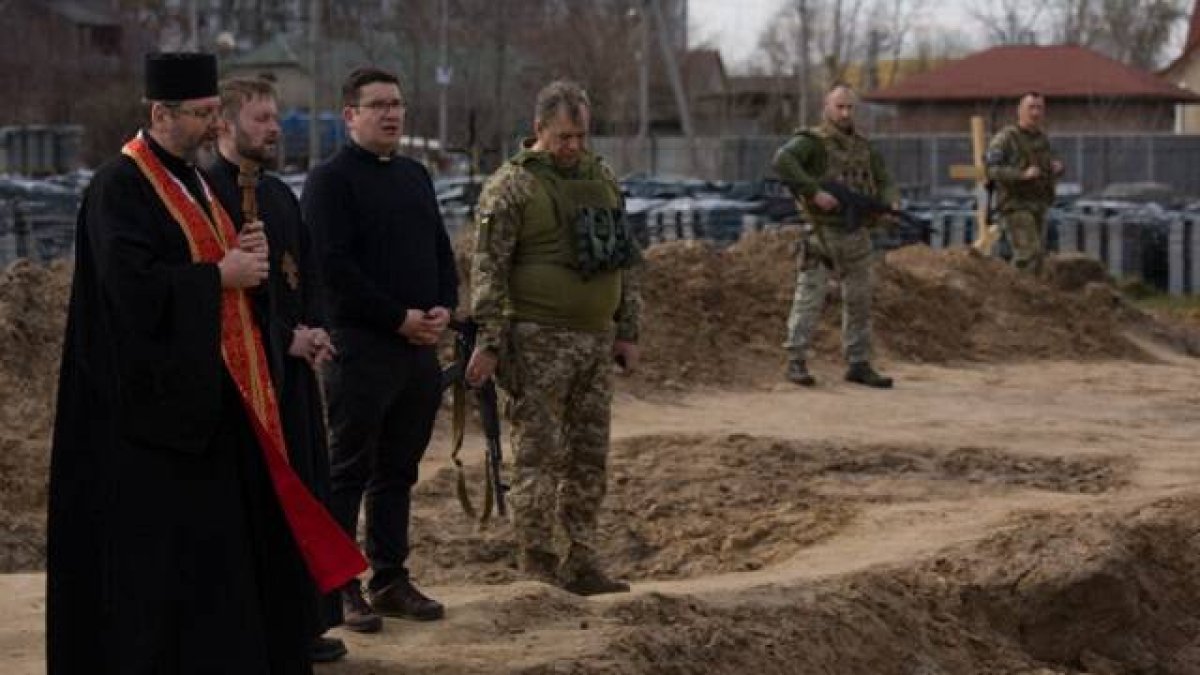 El arzobispo Shevchuk, con dos asistentes y militares ucranianos, ante la fosa común de Bucha el 7 de abril