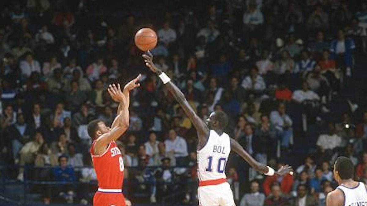 Primer jugador africano en llegar a la NBA, militó diez temporadas en la liga y se convirtió en uno de los mejores taponadores de la historia. Fue convocado a participar en las reuniones de paz en Sudán y presionado a convertirse al Islam.