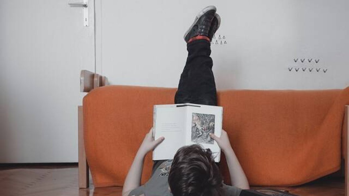 Un joven leyendo, quizá libros de Cuaresma, en una postura peculiar, en una foto de Anita Jankovic para Unsplash