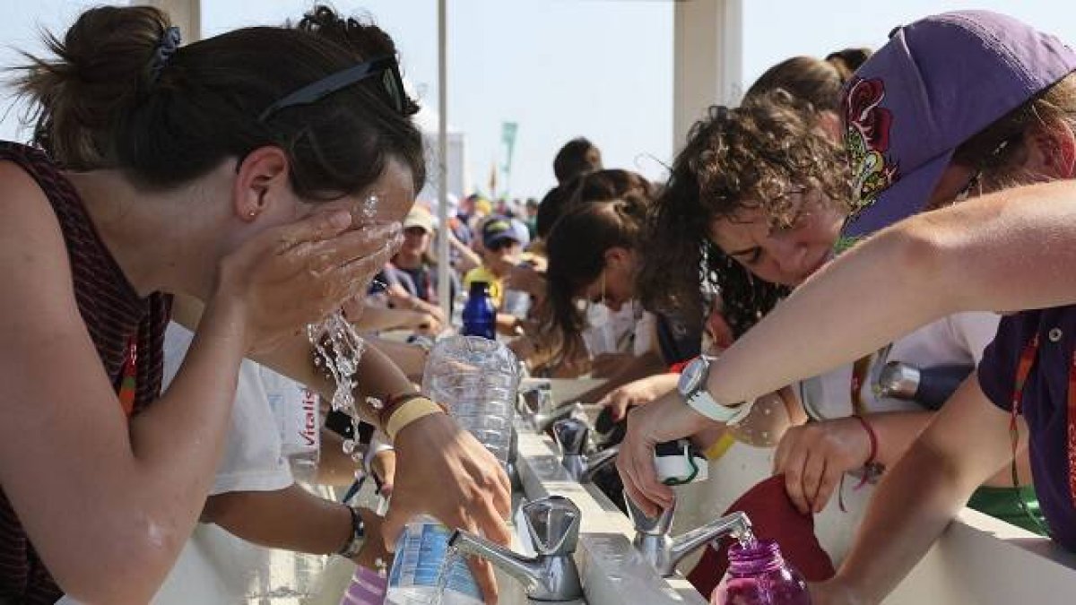 Peregrinos acalorados consiguen lavarse en uno de los escasos puntos de agua en el Parque del Tajo en la JMJ de Lisboa