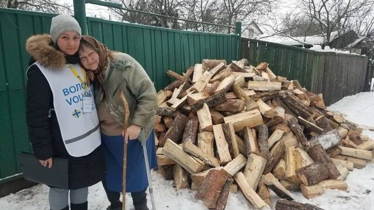 Una voluntaria de Cáritas repasa la entrega de madera para pasar el invierno a una anciana en Ucrania