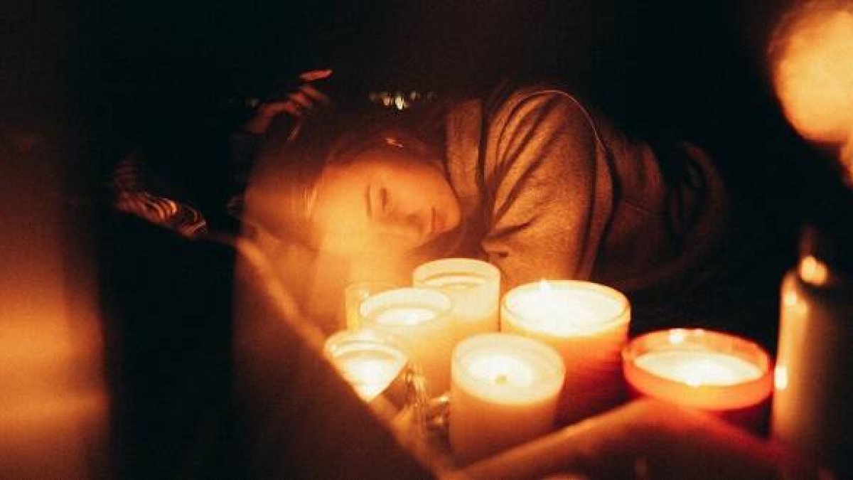 Una mujer joven con velas, quizá orando, en una foto de Harvey Robinson para Unsplash