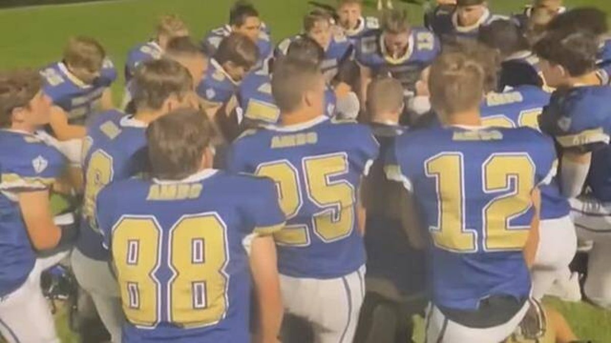 Una escena del vídeo que se viralizó, que muestra a los integrantes del equipo colegial de fútbol americano rodilla en tierra, rezando un avemaría antes del partido, según es su costumbre.