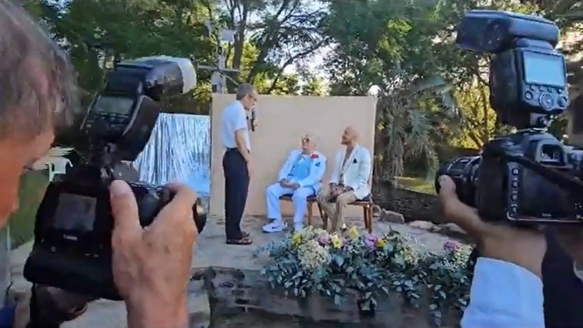 El padre Francisco Gordalina se dirige a Carlos Perciavalle y Jimmy Castilhos antes de bendecirles: testigos del acto, evidentemente no espontáneo, las cámaras de las prensa. Foto: captura vídeo 'El País'.
