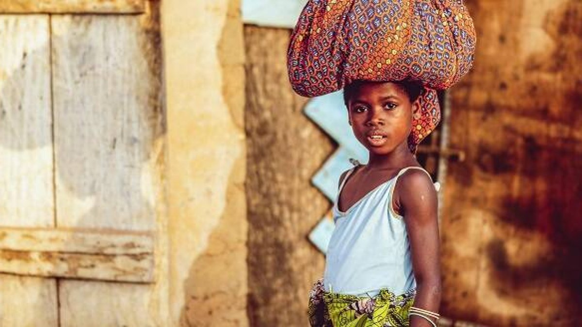 Una niña lleva cargas en la cabeza en Costa de Marfil... infancia y pobreza son temas de Dignitas Infinita... foto de Ben White en Unsplash