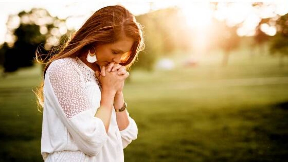 Una mujer en oración, en un campo luminoso, símbolo de esperanza