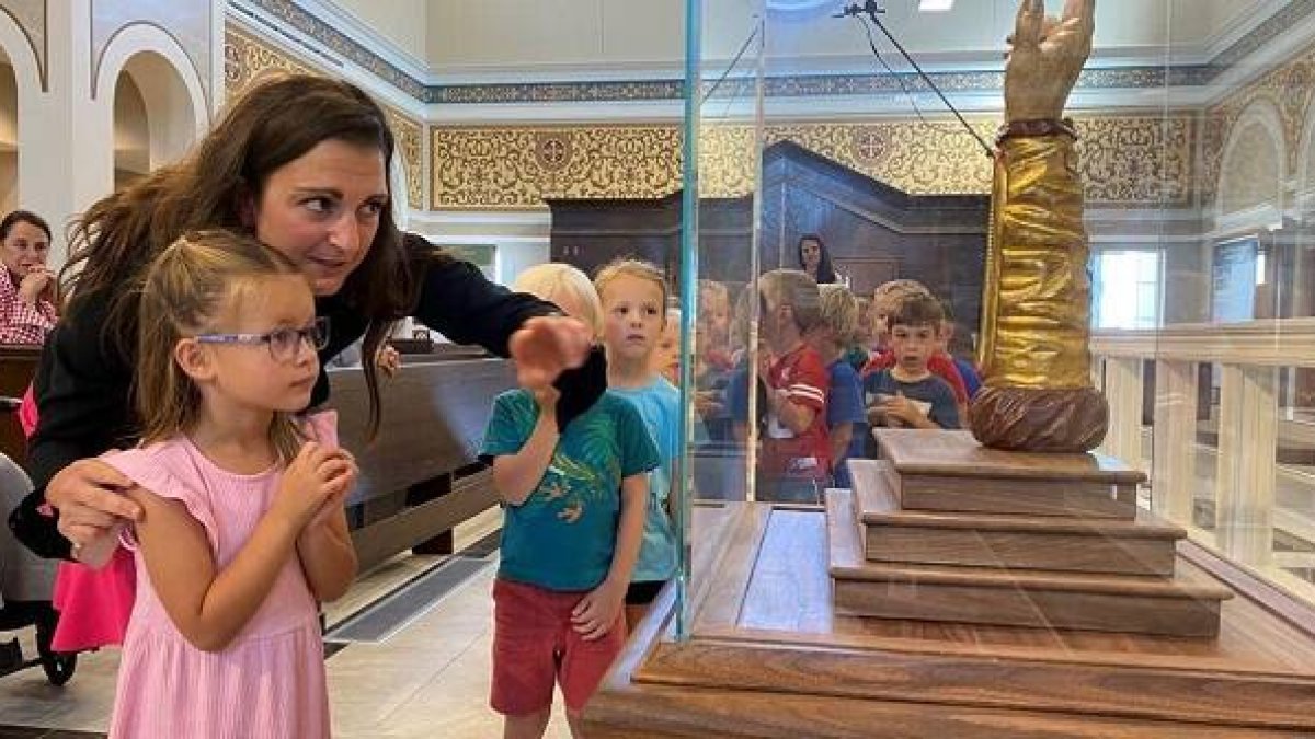 Unos niños asombrados y algo medrosos ante la reliquia del brazo de San Judas Tadeo en Nebraska