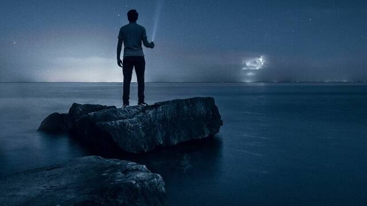 Un hombre busca la luz entre el cielo estrellado y el mar, símbolo de la verdad . foto de Warren en Unsplash