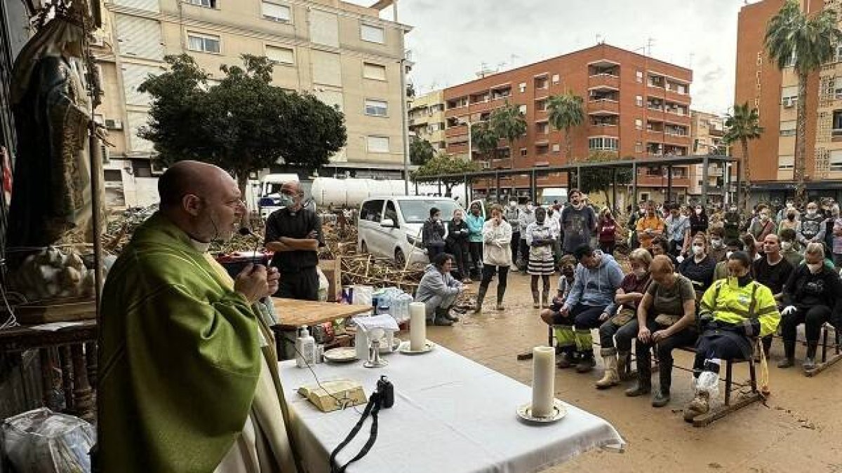 Misa de domingo en la calle ante María Madre de la Iglesia, en Catarroja, Valencia, con parroquianos y limpiadores