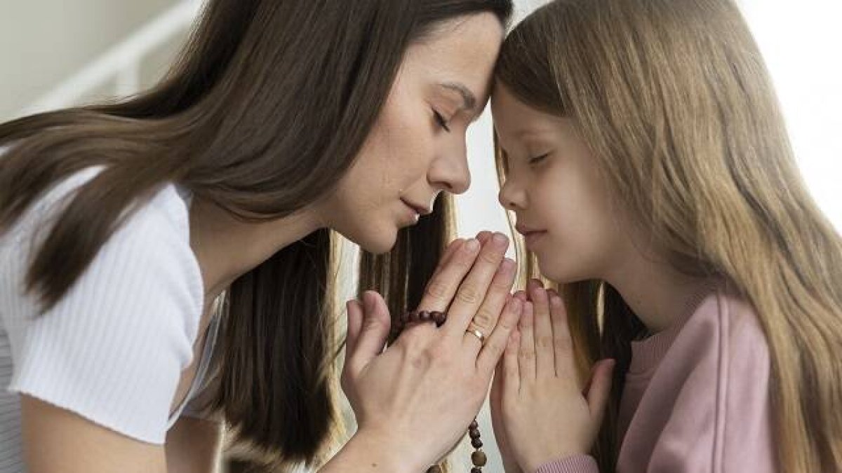 Una madre joven y su hija rezan con el Rosario