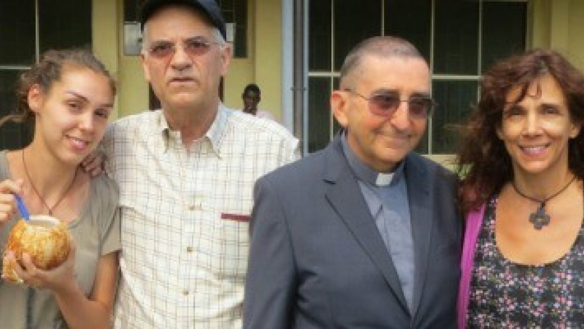 El padre Aldo Marchesini, vetsido con clérguiman y acompañado de unos colaboradores