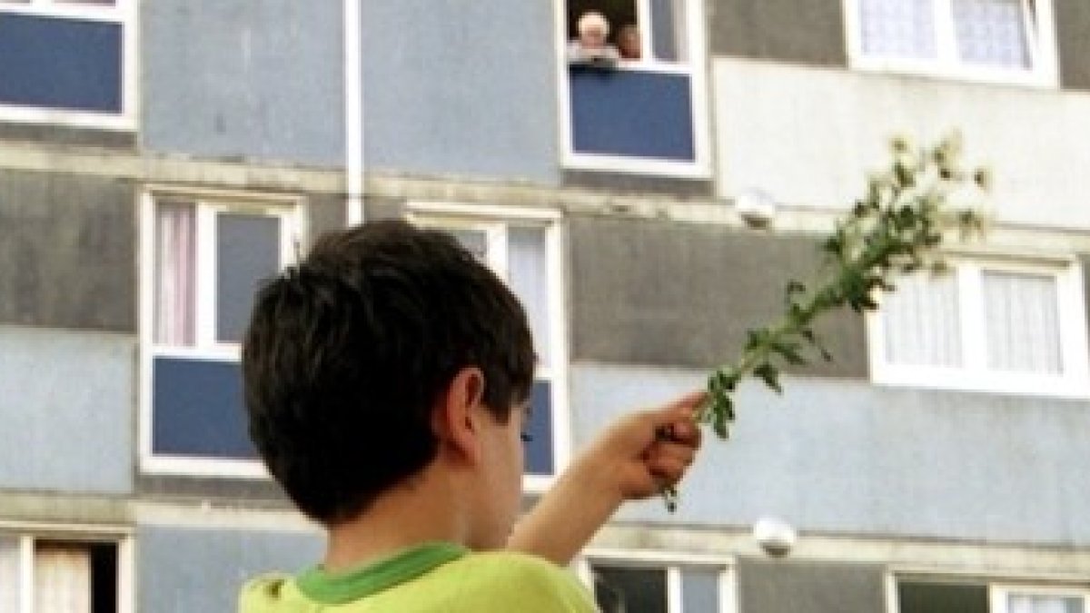 Un niño con una planta verde, signos de esperanza en los barrios HLM, grises, sucios, empobrecidos, envejecidos