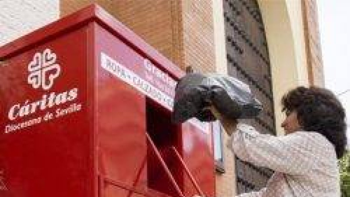 Un contenedor solidario de ropa de Cáritas Sevilla, junto a una iglesia... Cáritas tiene más de 13.500 voluntarios en Andalucía