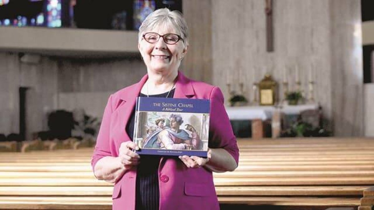 Christine Panyard muestra el libro que consagró a la Capilla Sixtina de Miguel Ángel. Foto: Detroit Catholic.