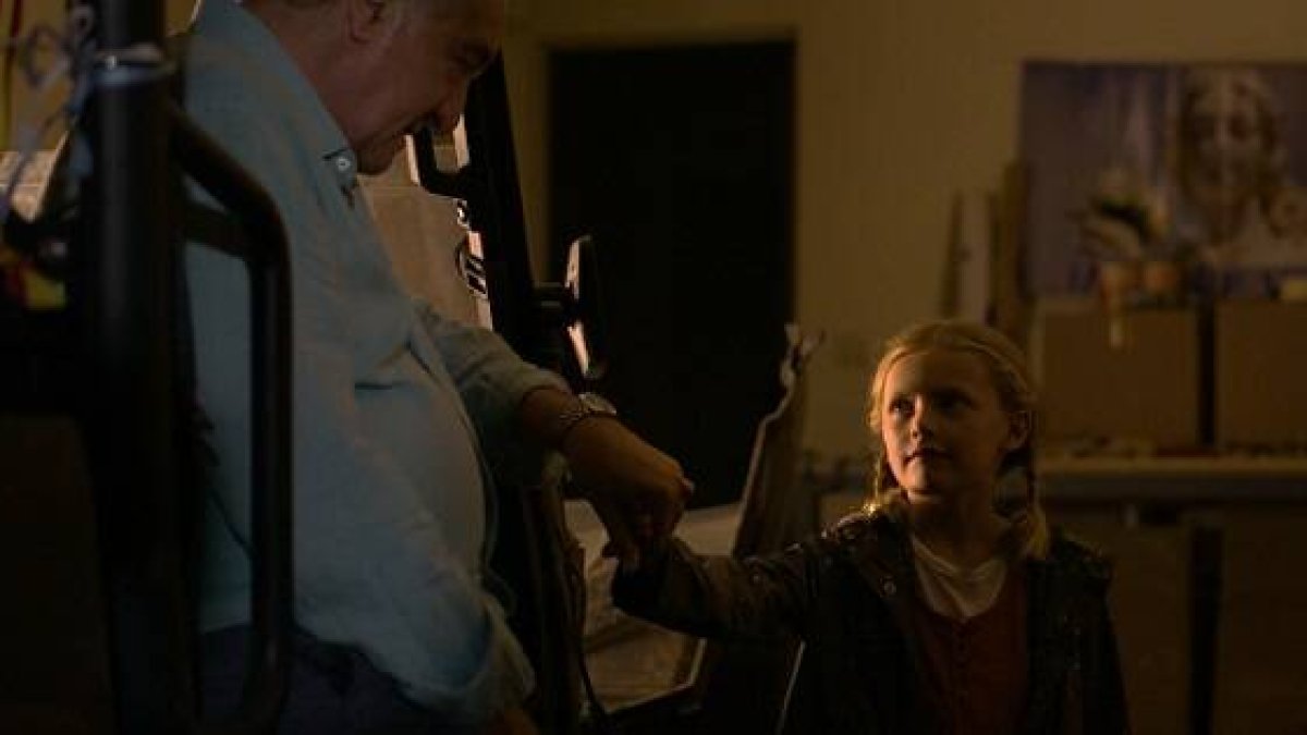 Una niña y un anciano, y de fondo la Virgen - una escena de la película Madre Ven