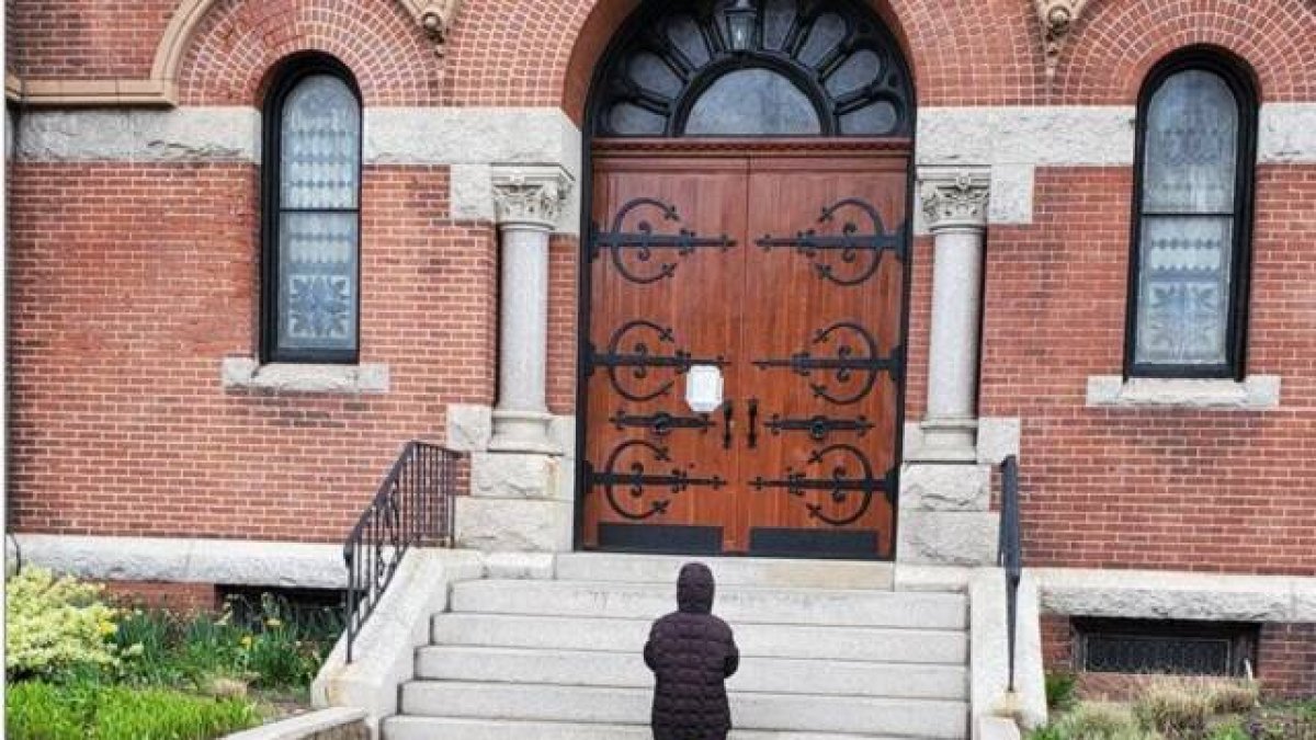 Una mujer reza ante la parroquia de Santa Teresa de Calcuta, en Dorchester, Boston, EEUU, cerrada por la pandemia, en 2020