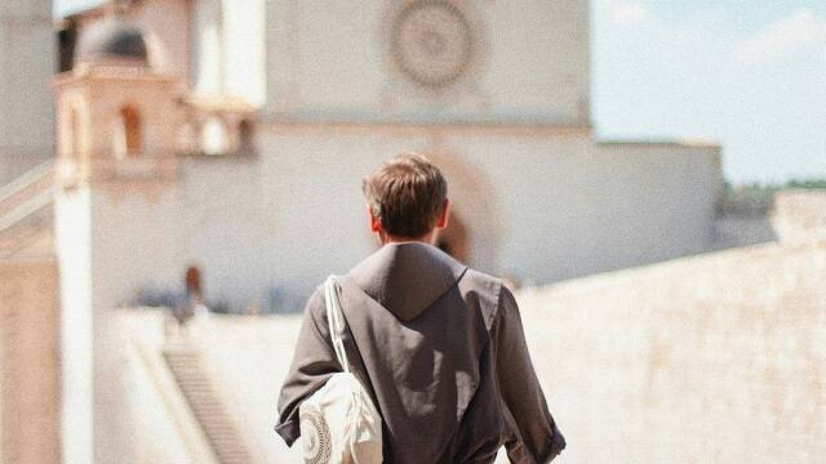 Un joven monje ante una iglesia en Asís, el hombre de hoy ante el misterio de Dios