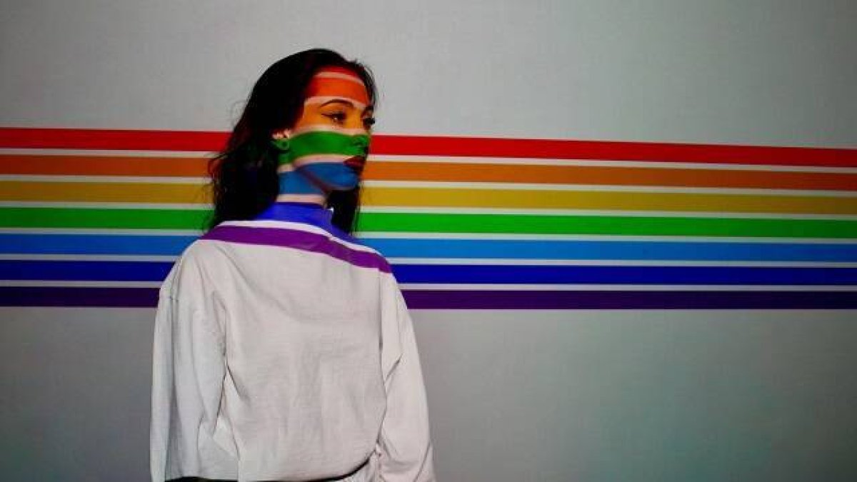Una mujer con fondo de la bandera arcoíris.