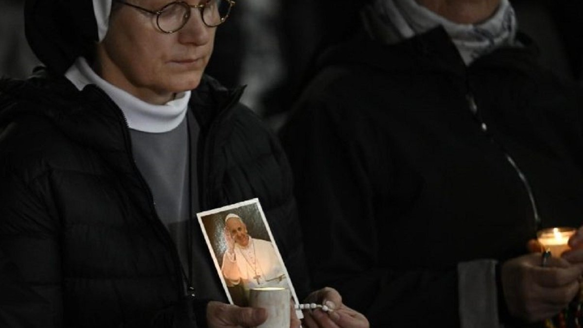 Unas religiosas rezan por el Papa Francisco, con velas y rosarios, de noche