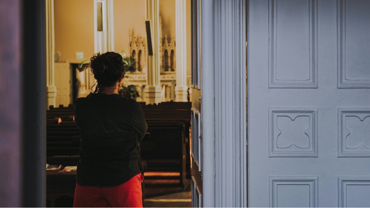 Una mujer a la entrada de una capilla, quizá orando sin entrar