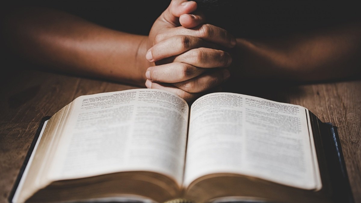 Un hombre rezando con la Biblia.